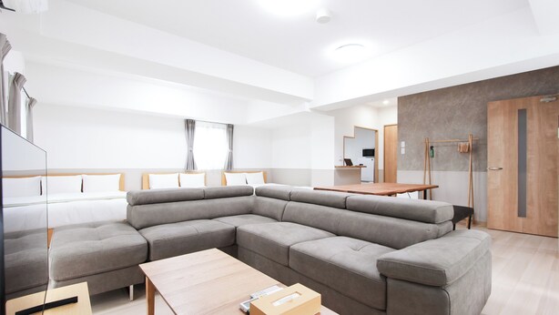 Ein modernes Wohnzimmer mit einer Eckcouch, einem Holztisch und einer Glastrennwand.