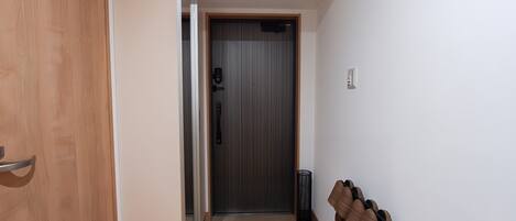 A hallway with a wooden door, a grey door, and a trash bin.