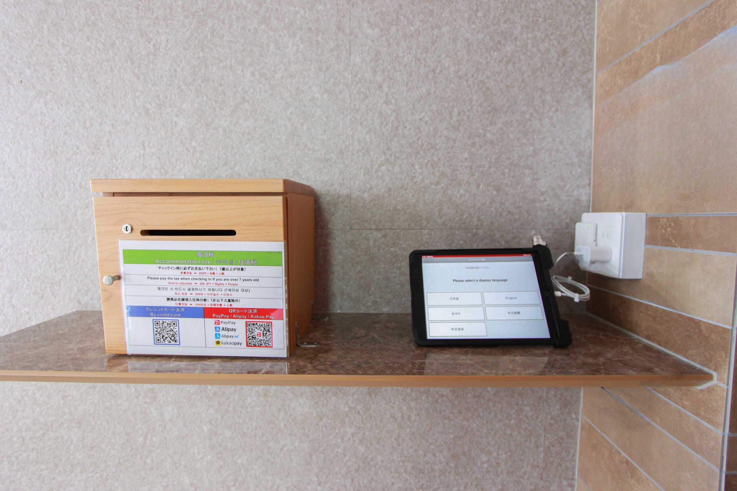 Un terminal de pago y una caja de madera con códigos QR e instrucciones para métodos de pago.