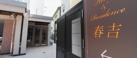 L’entrée d’un hôtel, avec une enseigne indiquant « Hôtel et résidence » et une flèche pointant vers la gauche.