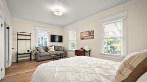A bedroom with a large bed, a sofa, a TV, and a window with blinds. - 240- History Buff, Sleeps 10, Central Location to FUN, Pet & Family Friendly (Jacksonville)
