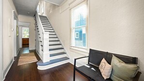 A staircase leading to a second floor, a bench with cushions, and a window with blinds. - 240- History Buff, Sleeps 10, Central Location to FUN, Pet & Family Friendly (Jacksonville)