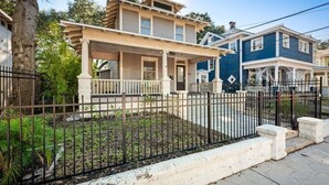 A two-story house with a porch and a fenced yard. - 240- History Buff, Sleeps 10, Central Location to FUN, Pet & Family Friendly (Jacksonville)