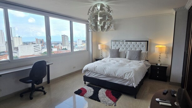 Habitación de hotel moderna con una cama grande, un escritorio y vistas a la ciudad.
