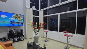 Una sala de estar moderna con un televisor de pantalla plana grande, una mesa de centro con un jarrón de flores y dos sofás con cojines coloridos.