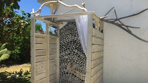 Une structure en bois avec un mur décoré d’une mosaïque de pierres et un rideau blanc.