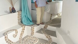 Une femme se tient sur un escalier dont le design particulier se caractérise par des motifs de pierres imbriquées.