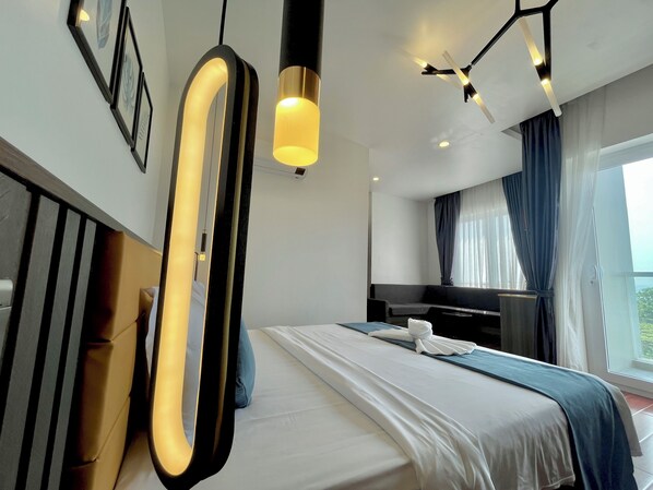 A modern hotel room with a large bed, a bedside table, a mirror, and a ceiling fan. - Kep Sea View Hotel (Kep)