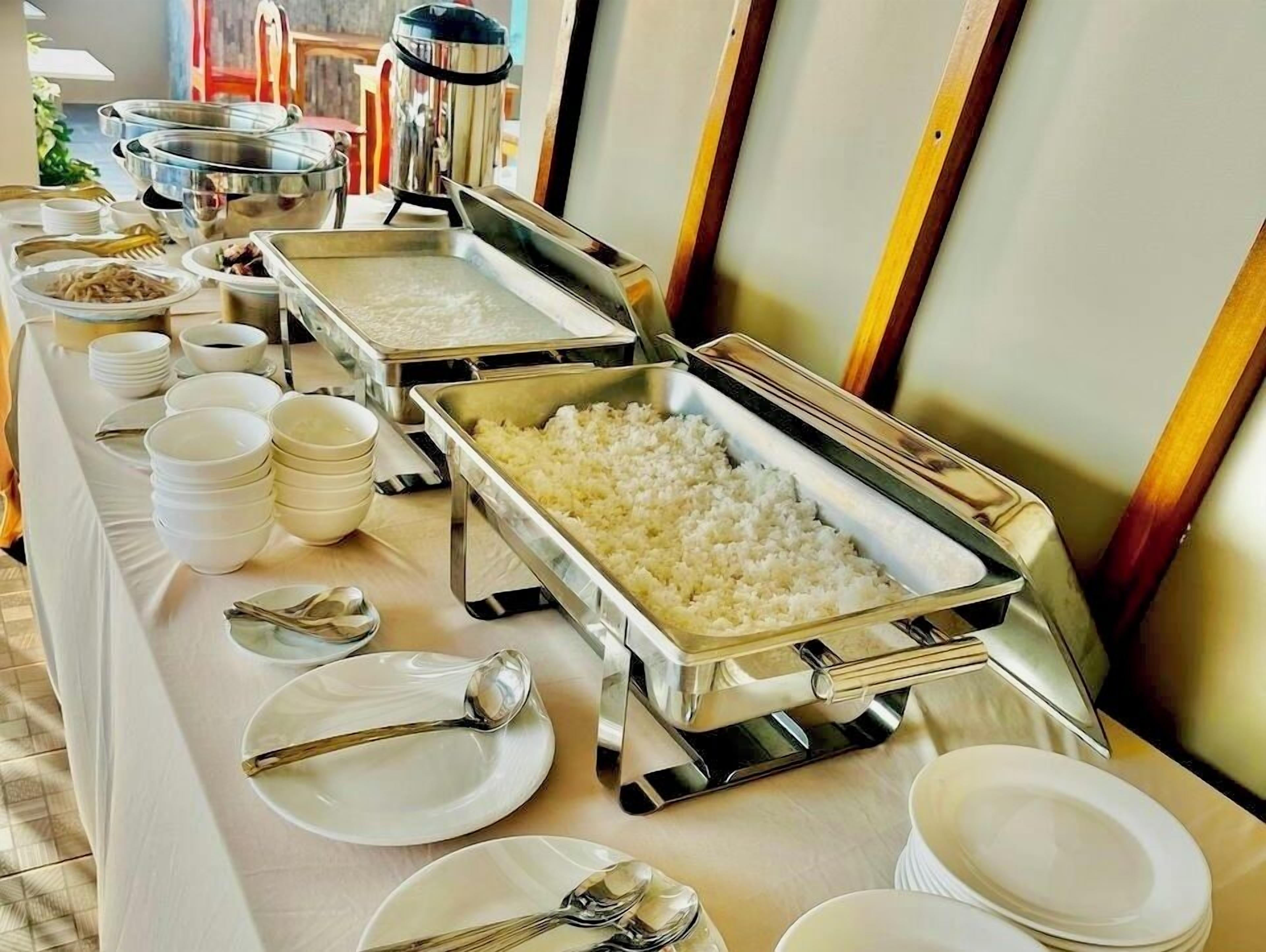 Montaje de bufé con múltiples fuentes de comida, incluyendo un recipiente grande de arroz, tazones y platos.