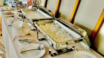 Montaje de bufé con múltiples fuentes de comida, incluyendo un recipiente grande de arroz, tazones y platos.