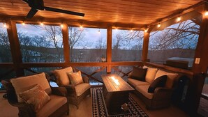 Un espace extérieur abrité, aménagé avec du mobilier en bois, des guirlandes lumineuses et offrant une vue sur le paysage.