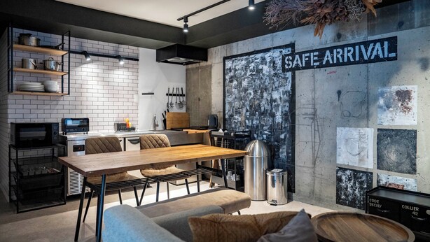 A modern kitchen with white subway tiles, a wooden dining table, and a black and white abstract wall art piece. - TAKETO STAY KOTONI 102 (Sapporo)