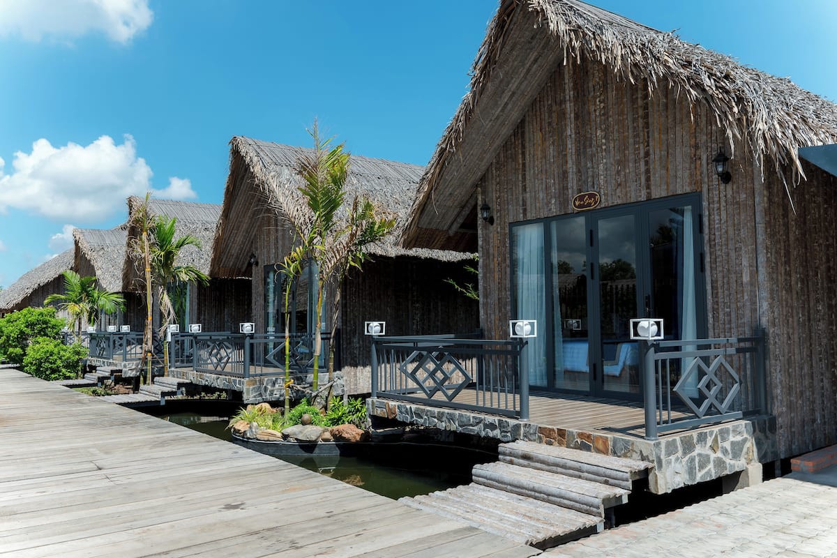 Wasserbungalows mit Strohdächern, Holzstegen und einem kleinen Wasserkanal.