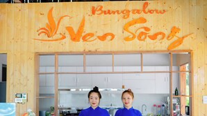 A wooden sign with the text "Bungalow Ven Sangs" and two individuals standing behind a counter. - BUNGALOW VEN SONG (Long Duc)
