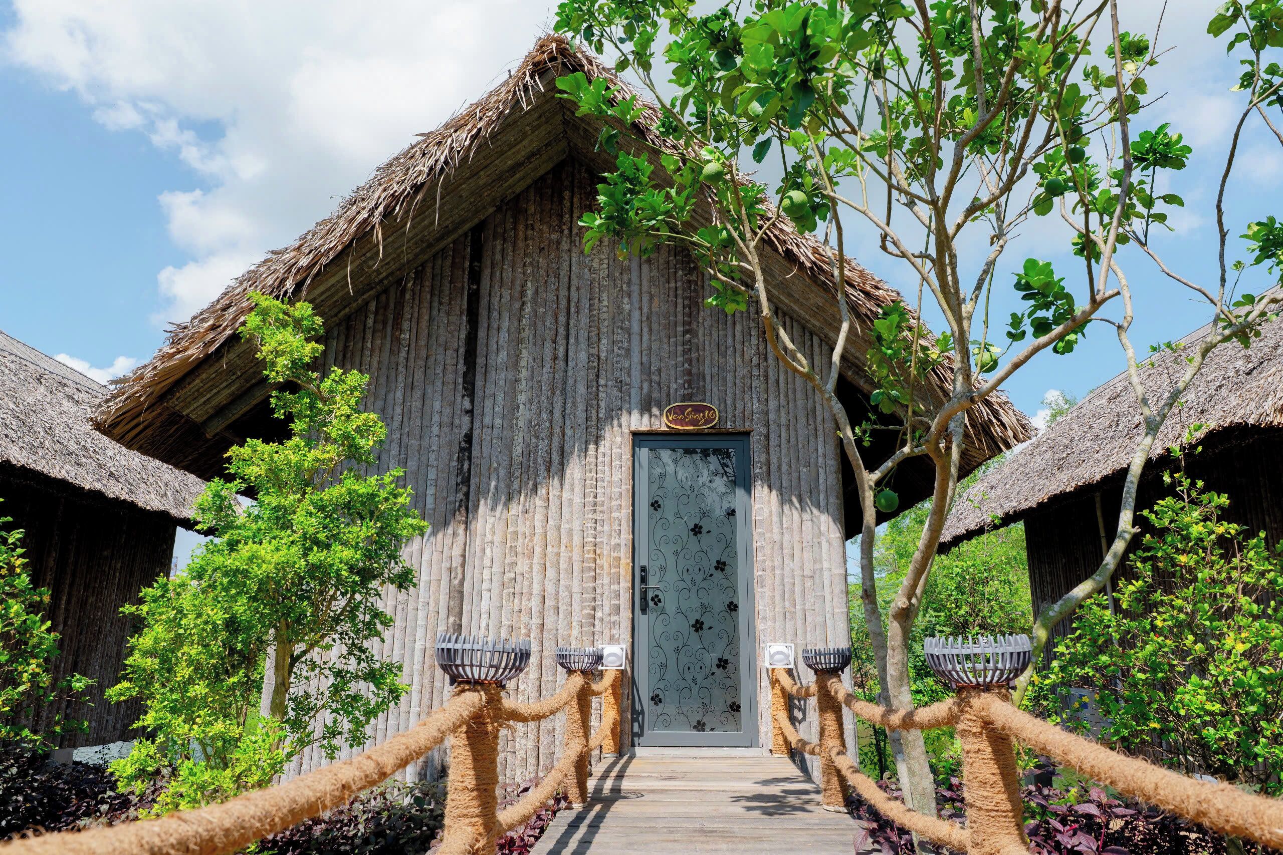 A rustic wooden building with a thatched roof, a decorative door, and rope barriers leading to the entrance.