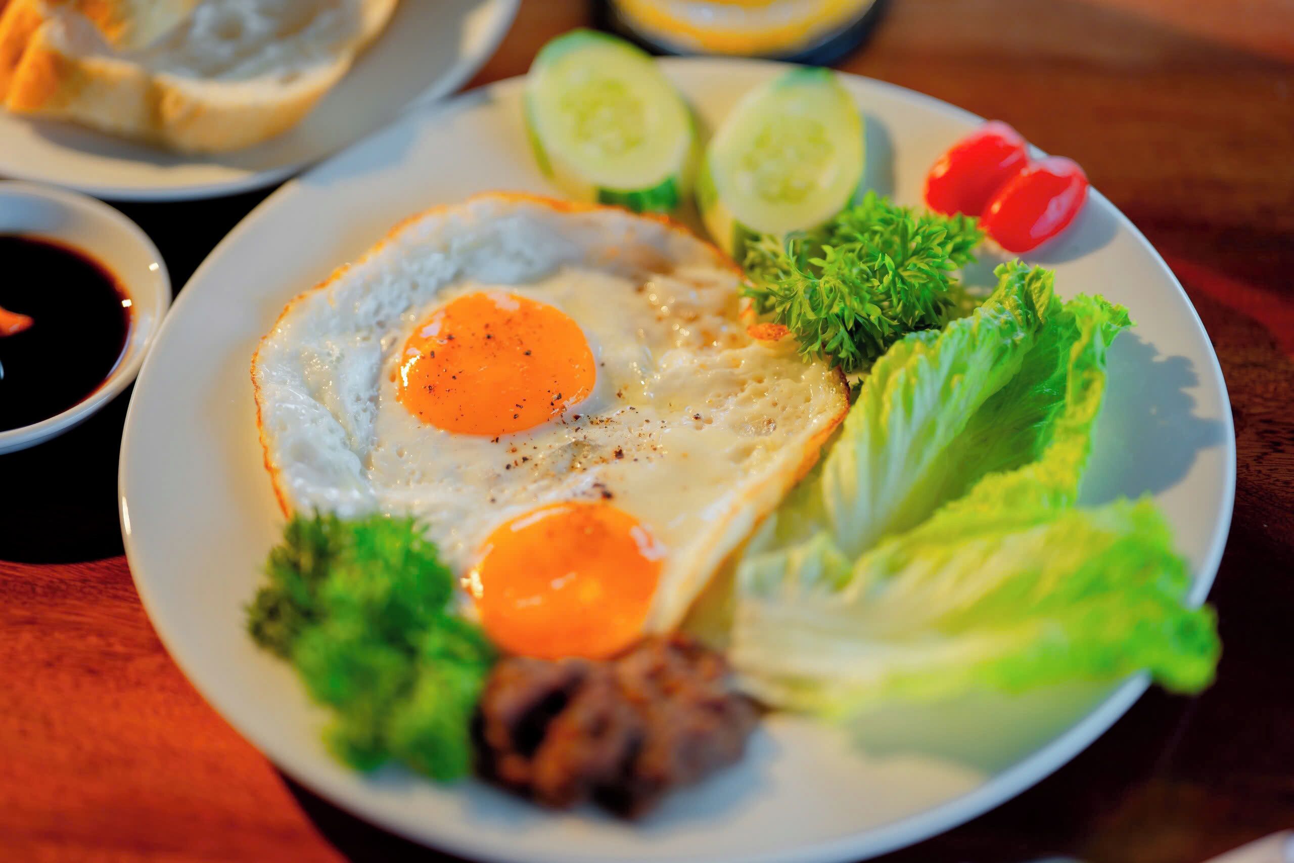 A plate with a fried egg, lettuce, cucumber slices, and a small tomato.