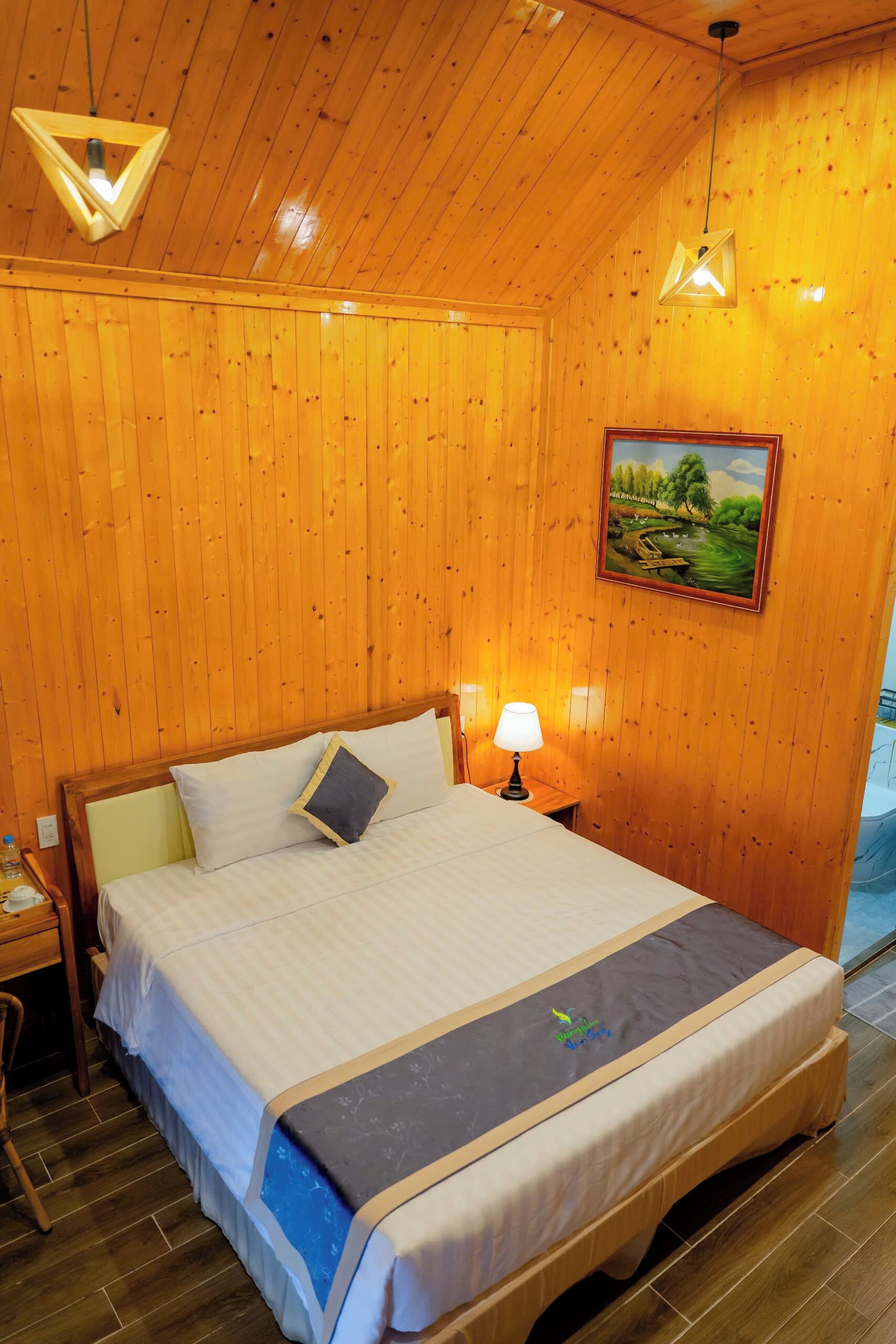 Una habitación con paneles de madera, una cama, una mesita de noche, una lámpara y un cuadro en la pared.