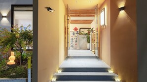Un escalier menant à une pièce dont le plafond est en bois et sur laquelle on peut voir une enseigne avec des caractères chinois.