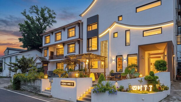 Un hôtel moderne à plusieurs étages, doté d’une façade incurvée, d’un espace extérieur aménagé et d’une enseigne lumineuse.