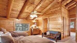 A log cabin bedroom with a bed, a chair, a dresser, and a ceiling fan. - Beautiful Log Cabin at Bear Mountain Resort (Big Bear Lake)
