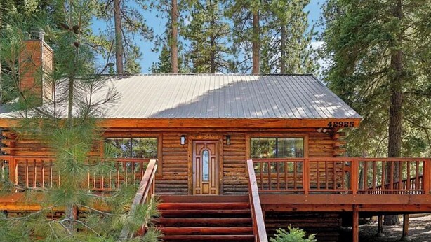 A log cabin with a metal roof, a wooden deck, and a staircase leading to the entrance. - Beautiful Log Cabin at Bear Mountain Resort (Big Bear Lake)