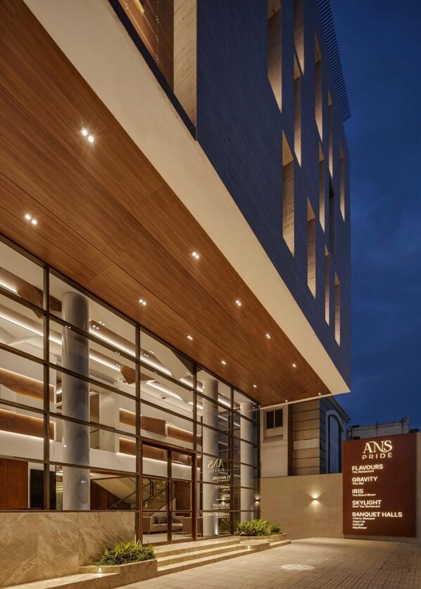 A modern hotel exterior with a prominent entrance, large glass windows, and a well-lit facade. - HOTEL ANS PRIDE (Pudukkottai)