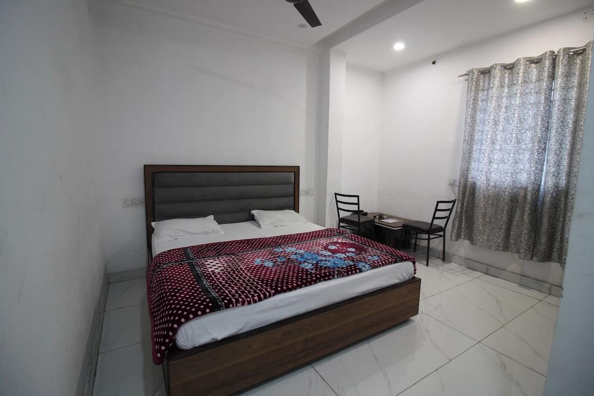 A bedroom with a bed, a desk, and chairs.