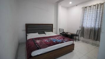 Un dormitorio con cama, escritorio y sillas.