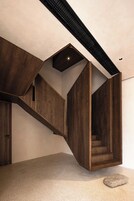 Un interior moderno con una escalera de madera, un tragaluz pequeño y un suelo de hormigón.