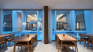 Un espace repas moderne avec des tables et des chaises en bois, de grandes fenêtres et une vue sur la piscine.
