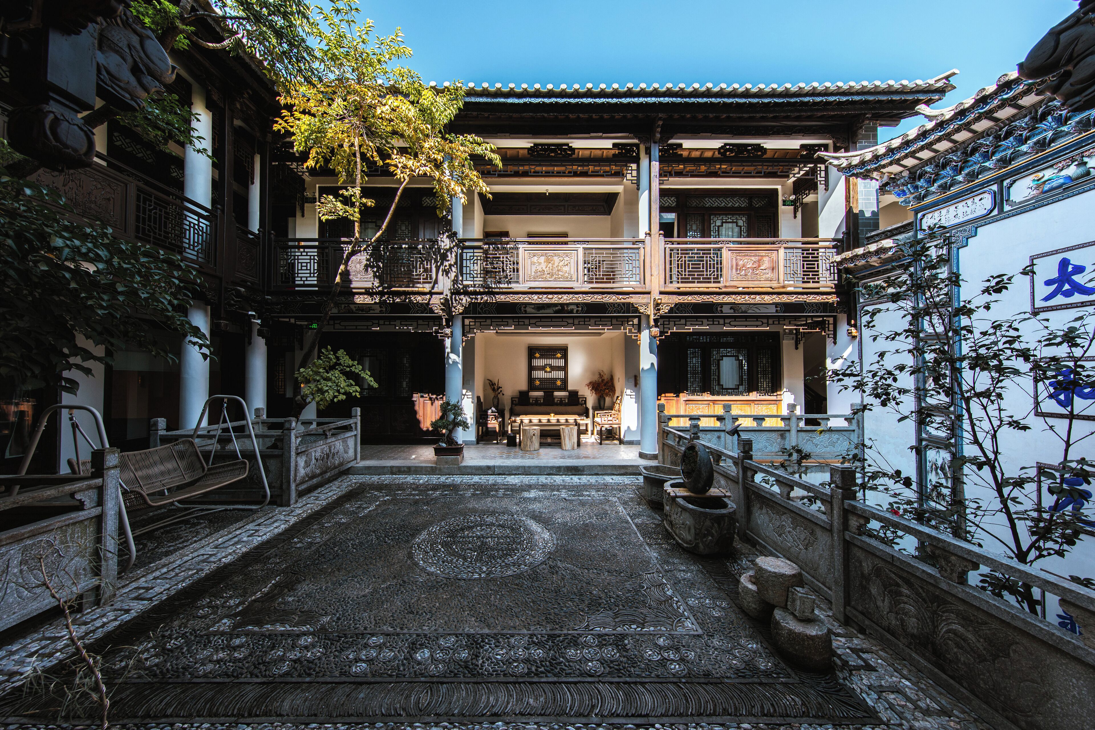 A traditional courtyard with a tiled floor, a wooden bench, and a stone balustrade.