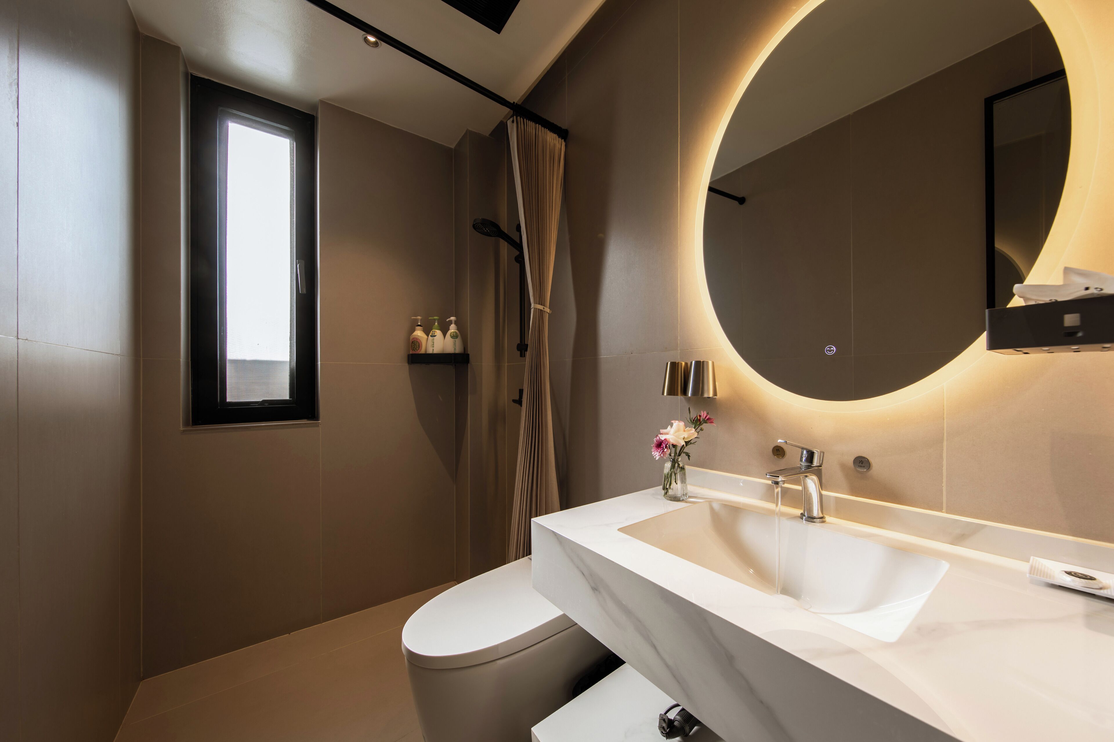 Un baño moderno con un lavabo blanco, un espejo grande y una cortina de ducha.