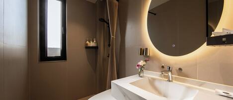 Un baño moderno con un lavabo blanco, un espejo grande y una cortina de ducha.