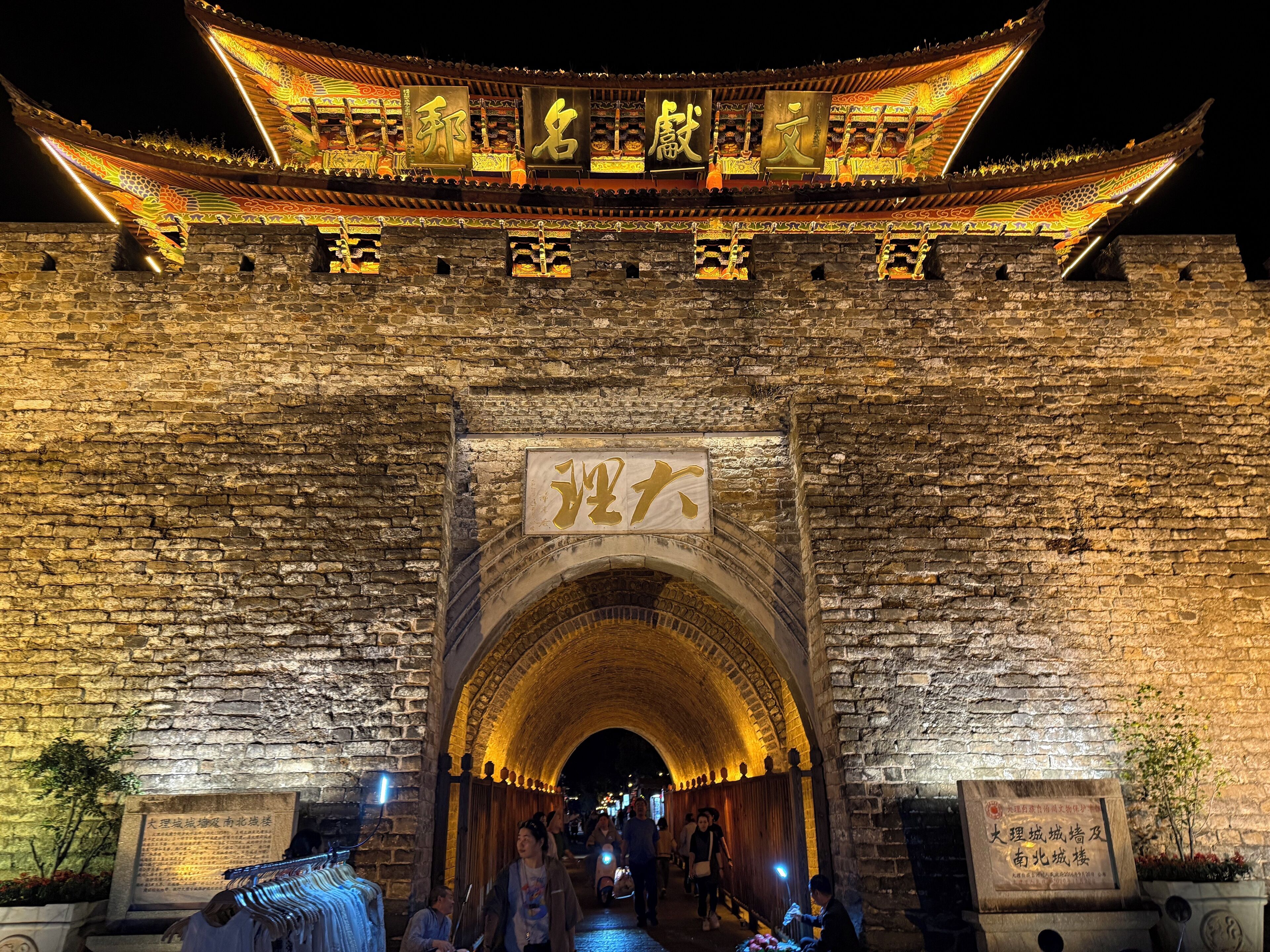 Una puerta tradicional china con adornos elaborados y letreros iluminados.