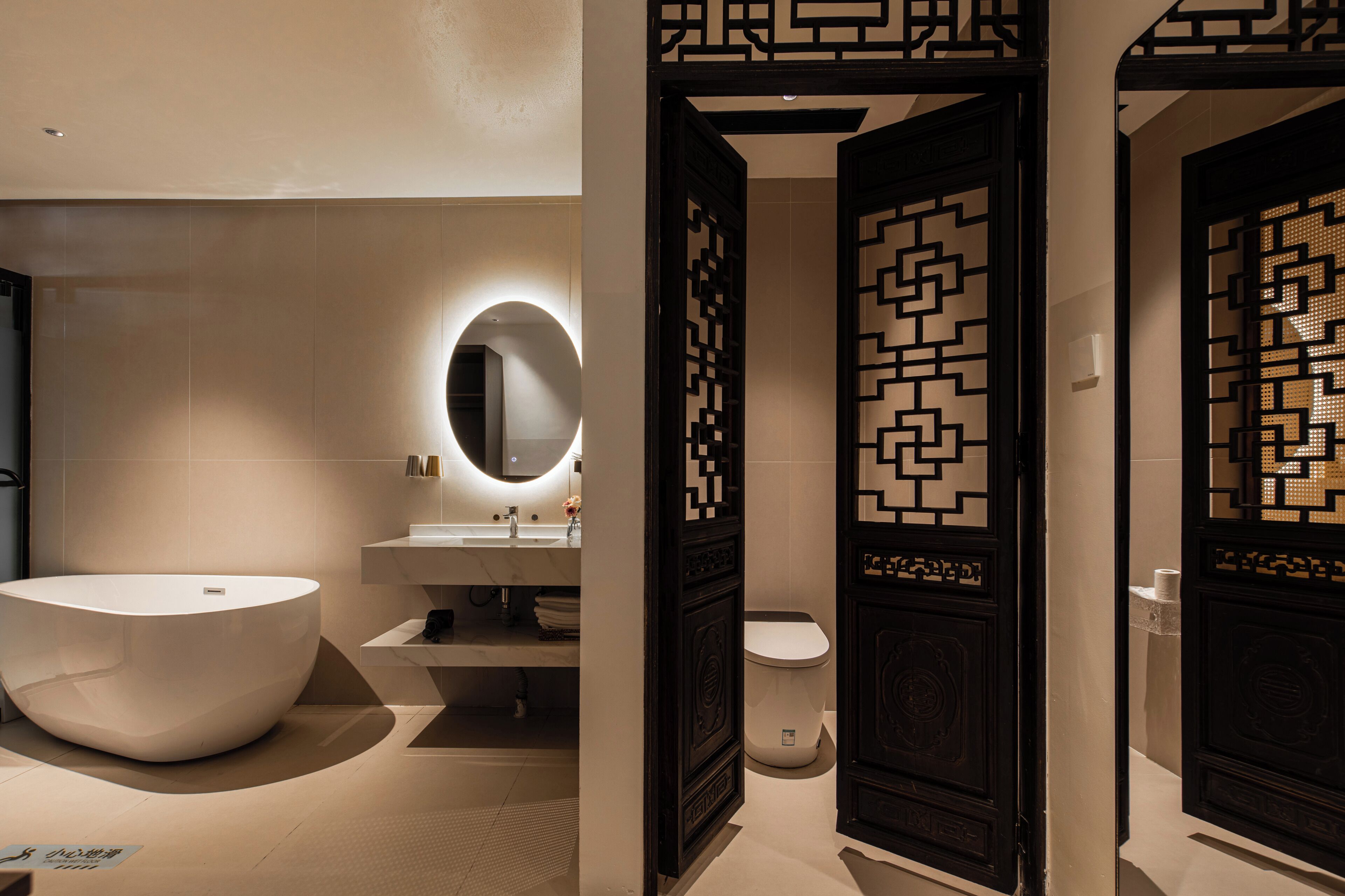 Een moderne badkamer met een groot ovaal wastafel, toilet en spiegel met een ronde lijst.