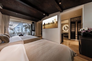Habitación de hotel moderna con una cama grande, un escritorio y vistas a un paisaje urbano a través del ventanal.