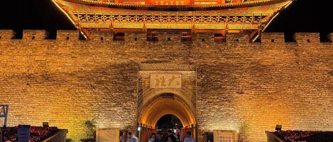 A traditional Chinese gate with intricate designs and illuminated by warm lighting.