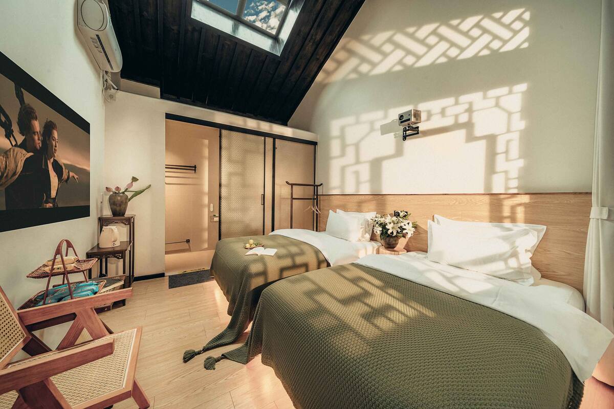 Una habitación de hotel moderna con dos camas, un ventanal grande y vistas a la montaña.