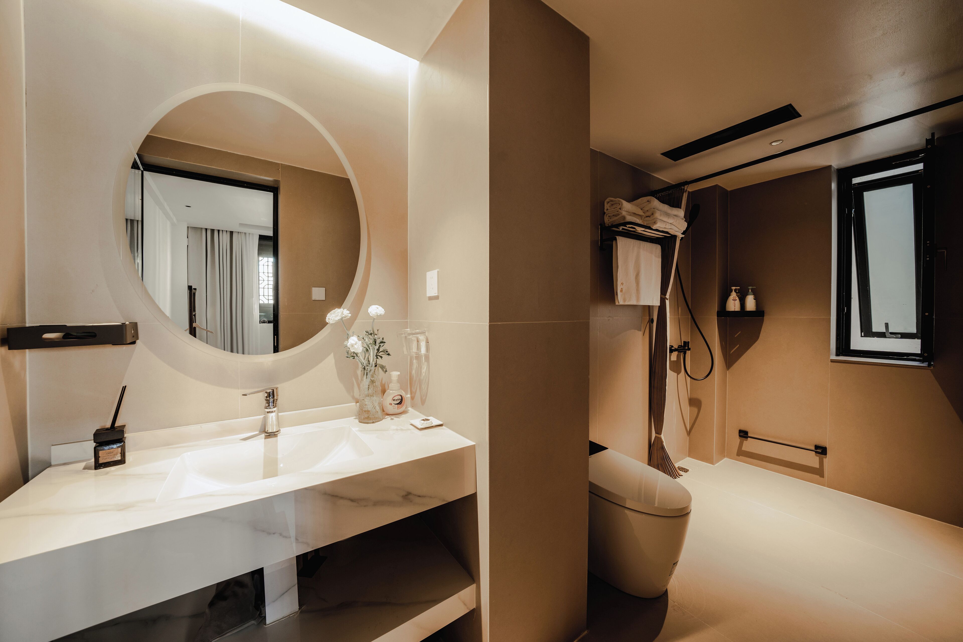 Een moderne badkamer met een grote spiegel, een witte wastafel en een toilet.