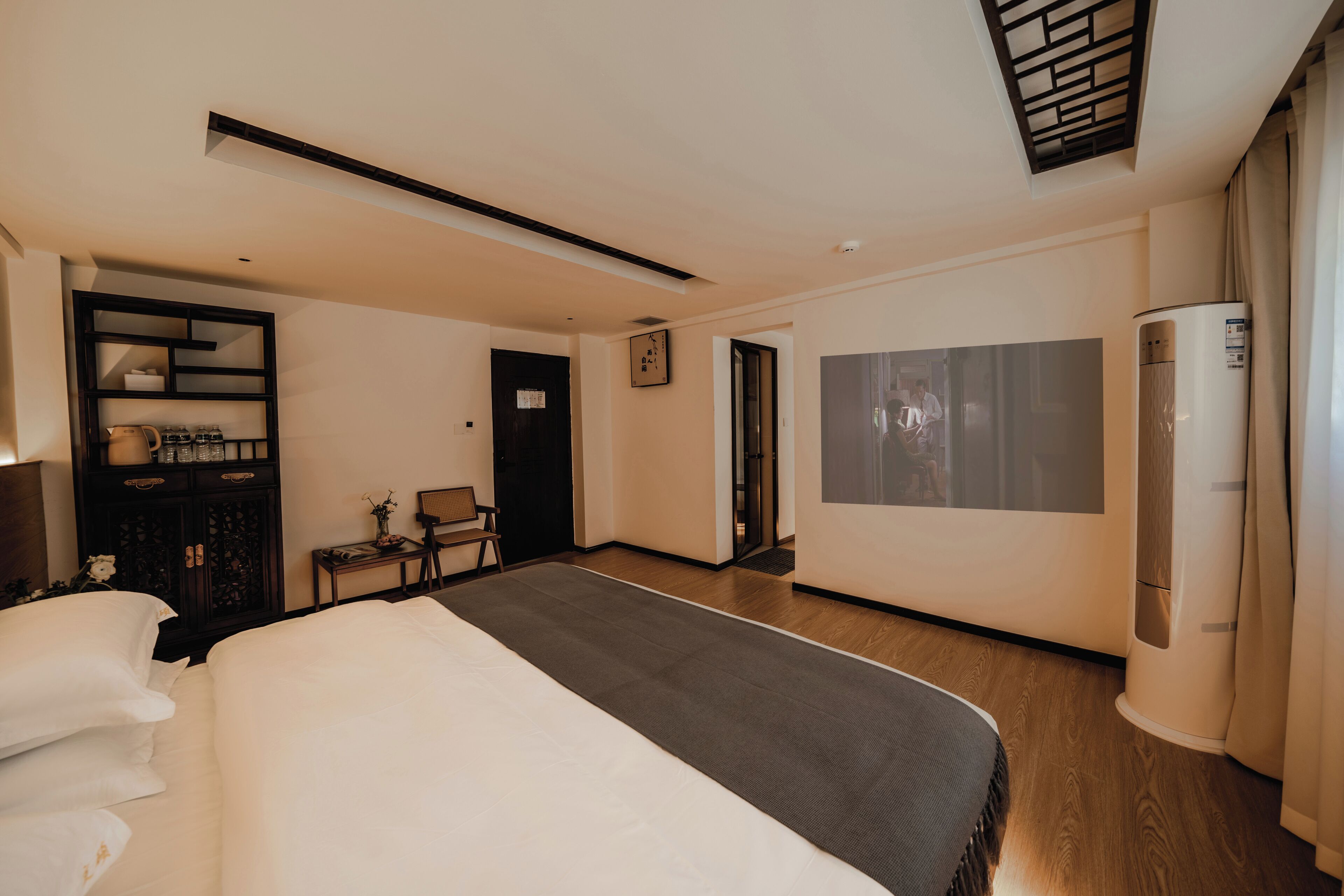 A hotel room with a large bed, a TV, a wardrobe, and a desk.