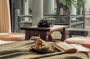 Una habitación acogedora con una mesa de madera, una cesta de mimbre con frutas y un libro sobre un tapete tejido.