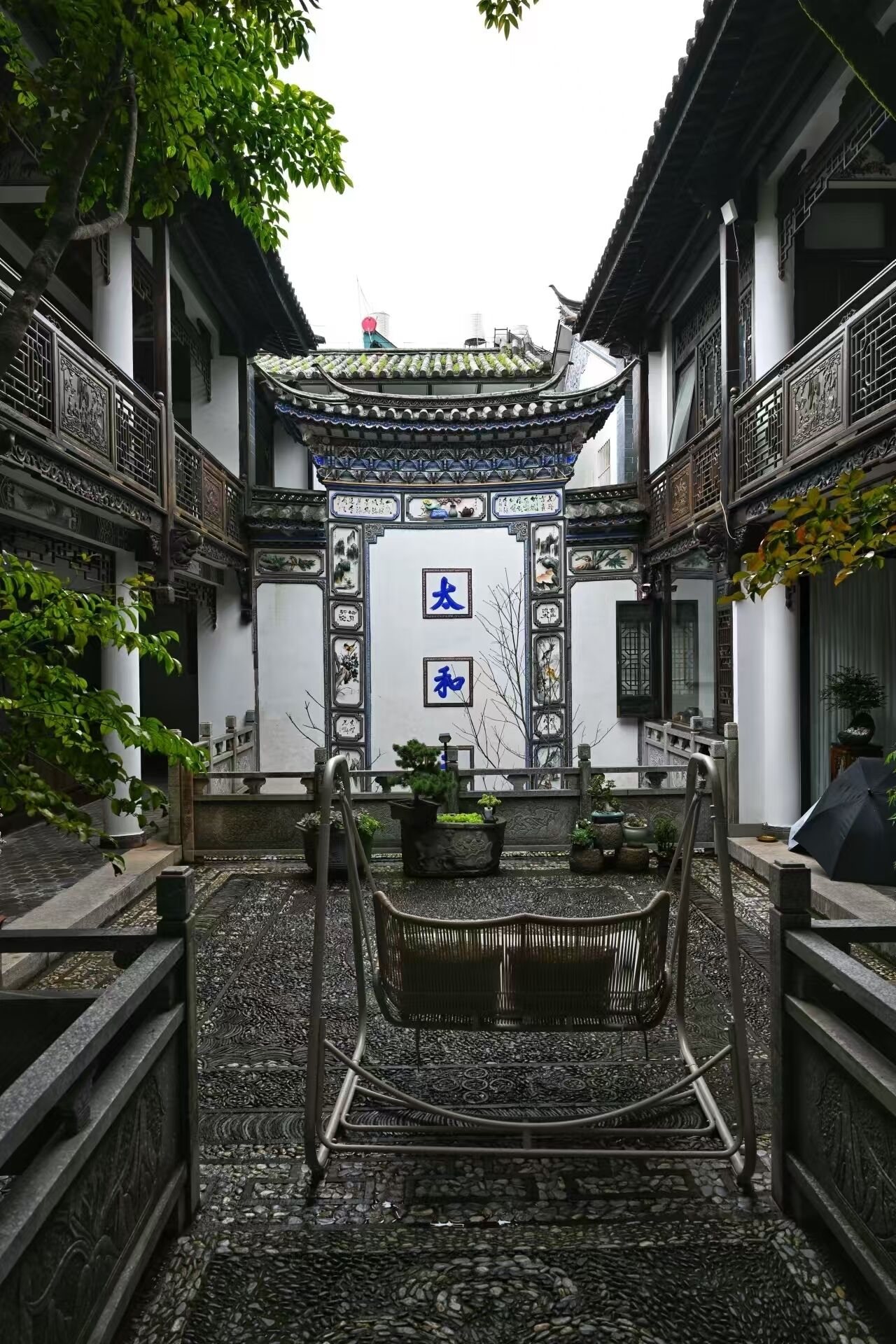 A traditional courtyard with a central staircase, surrounded by white walls with intricate designs and blue calligraphy.