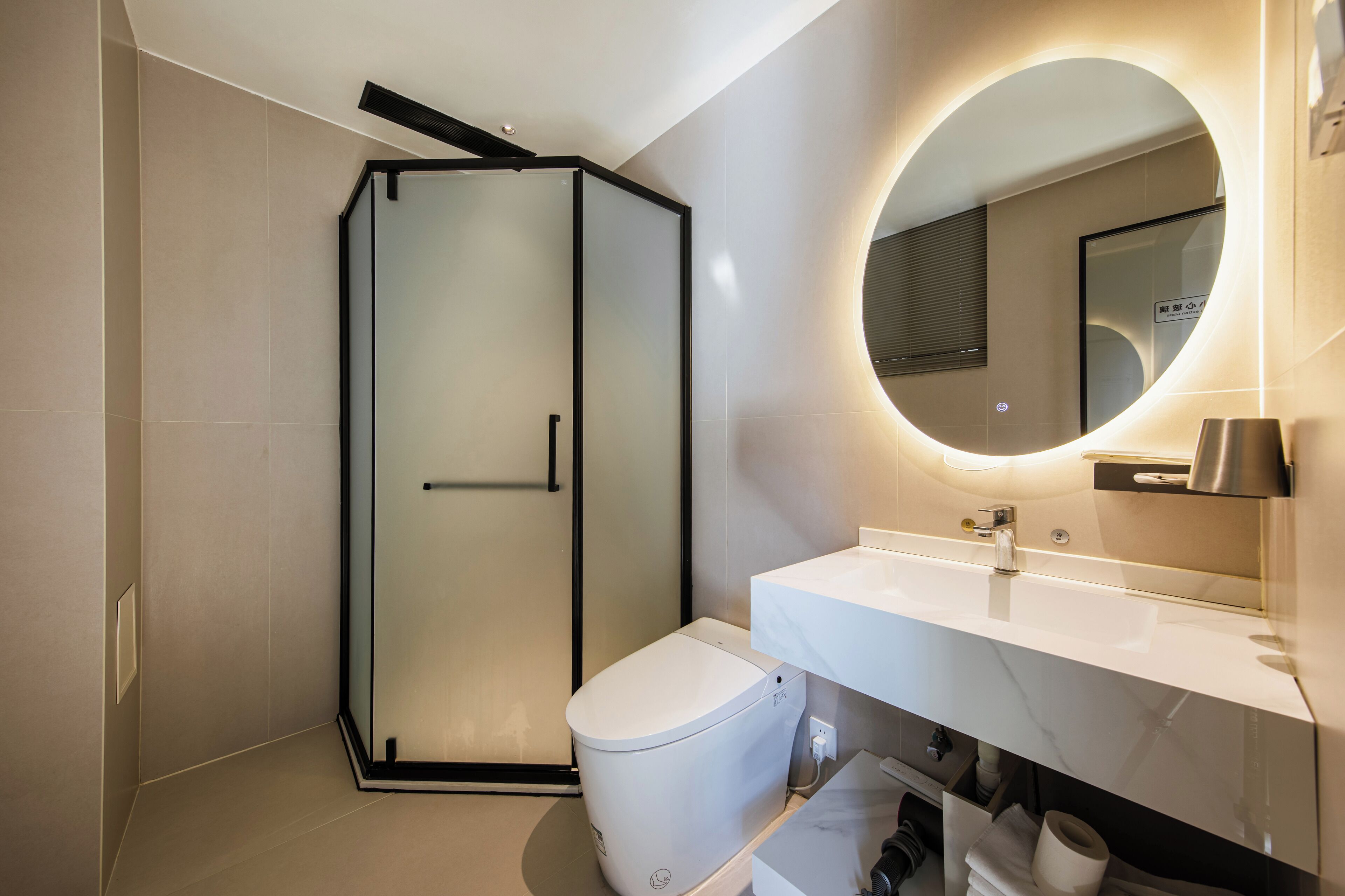 Un baño moderno con cabina de ducha de vidrio, inodoro blanco y tocador con espejo.