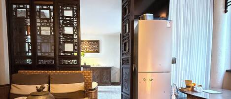 A traditional Japanese-style kitchen with a tatami mat table, a refrigerator, and various kitchen utensils.