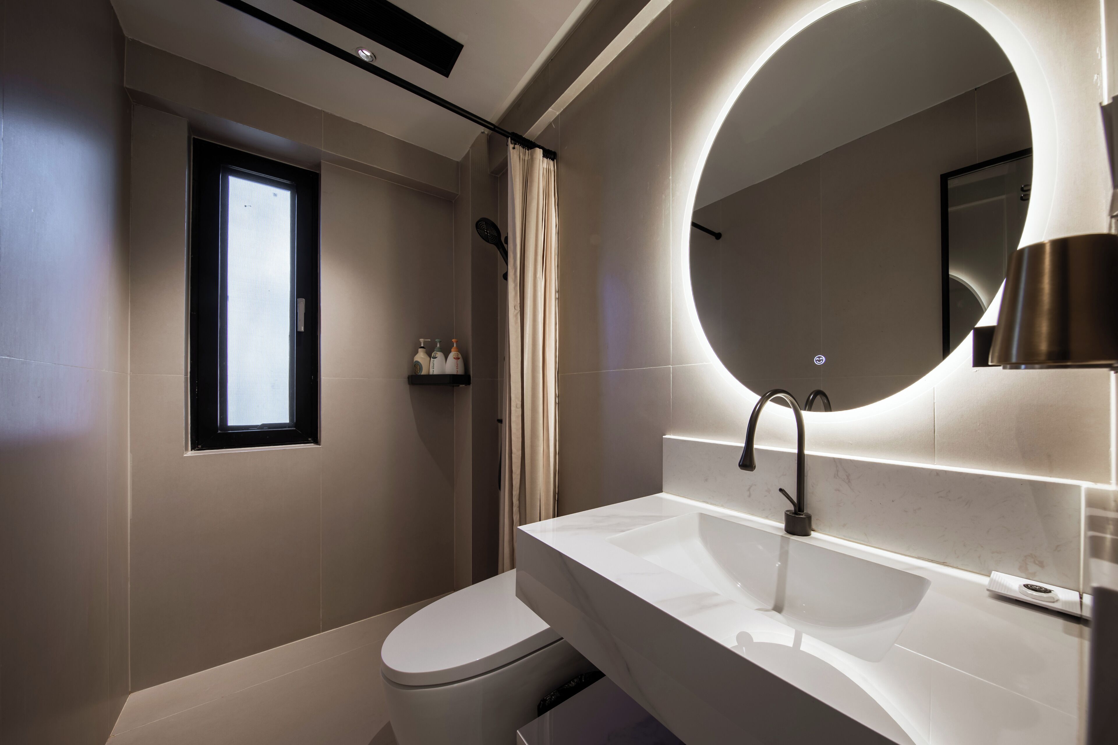 A modern bathroom with a white toilet, a large mirror, and a white sink.