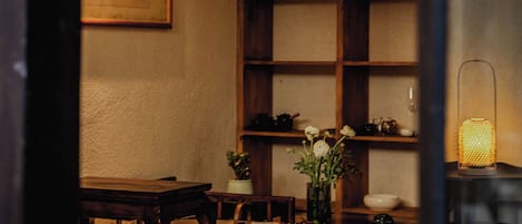 A dining area with wooden furniture, hanging pendant lights, and a vase with flowers.