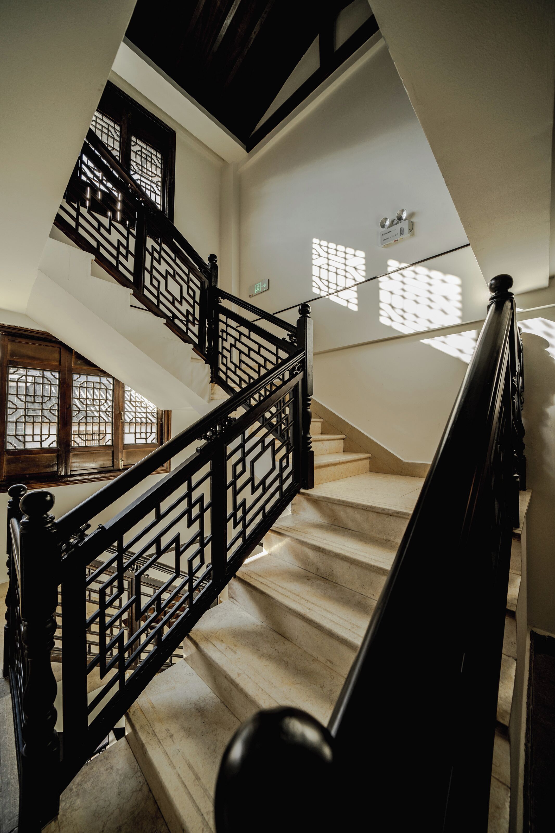 A staircase with black railings and a geometric pattern, leading to an upper floor.