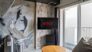 Ein modernes Wohnzimmer mit großem Fernseher an einer Holzwand, einem kleinen Holztisch und einer Couch mit Kissen.