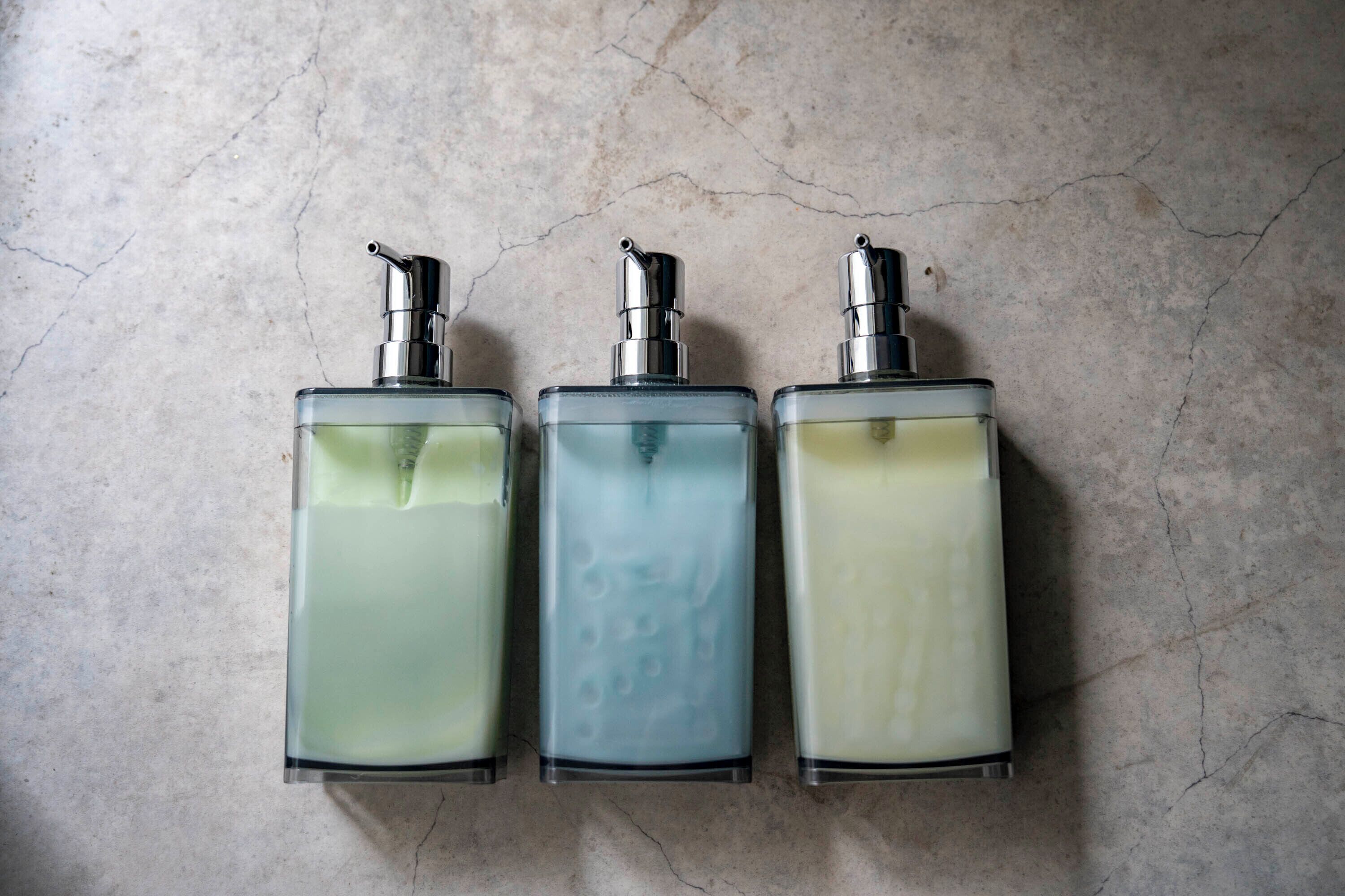 Three glass perfume bottles with pump dispensers on a textured surface.