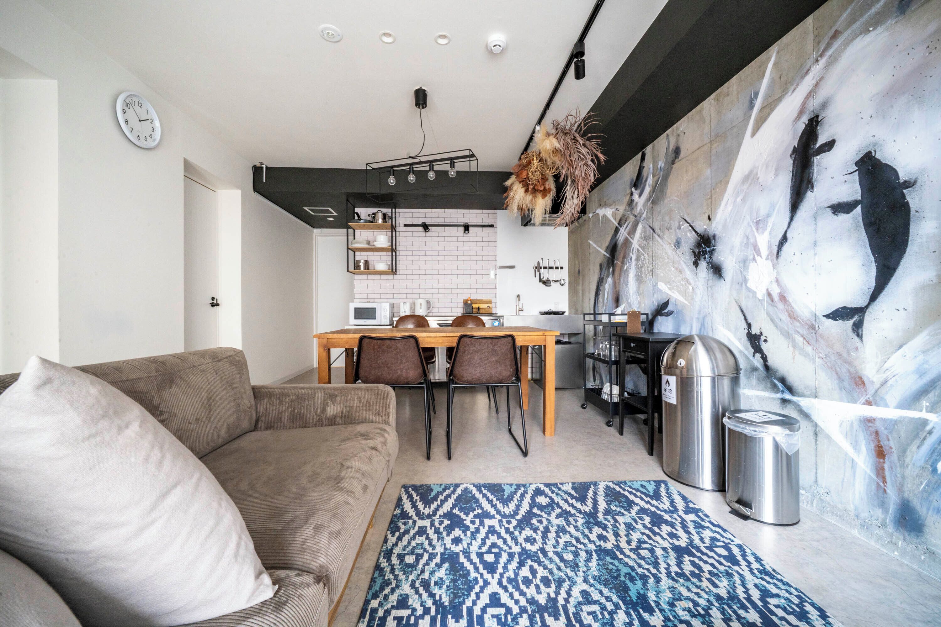 Una sala de estar moderna con un sofá, una mesa de comedor con sillas y una cocina al fondo.